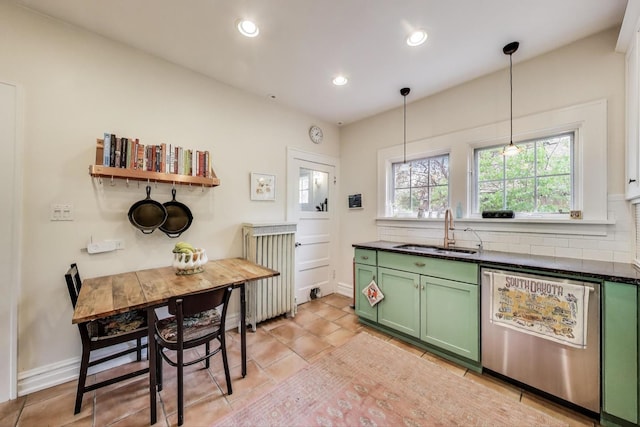 kitchen featuring green cabinetry, dishwasher, a sink, dark countertops, and decorative backsplash