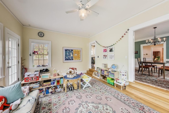 rec room featuring a chandelier, crown molding, wood finished floors, and ceiling fan