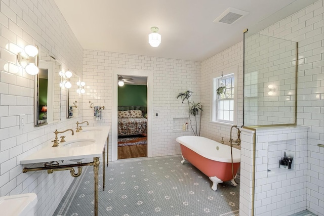full bath with tile walls, ensuite bath, a freestanding bath, a ceiling fan, and tile patterned floors