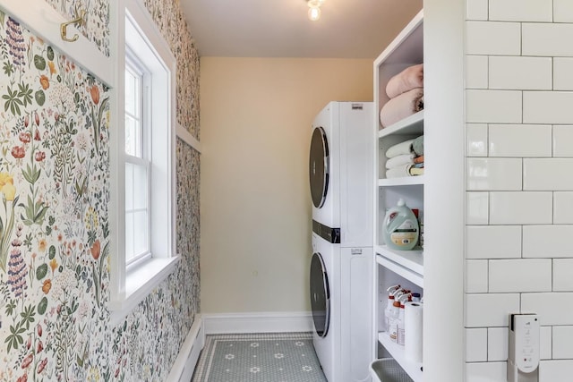 washroom featuring stacked washer and clothes dryer, tile patterned flooring, and baseboards