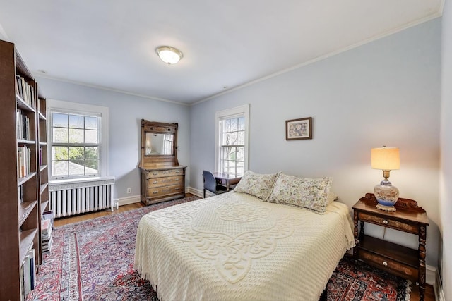 bedroom with radiator heating unit, wood finished floors, crown molding, and baseboards