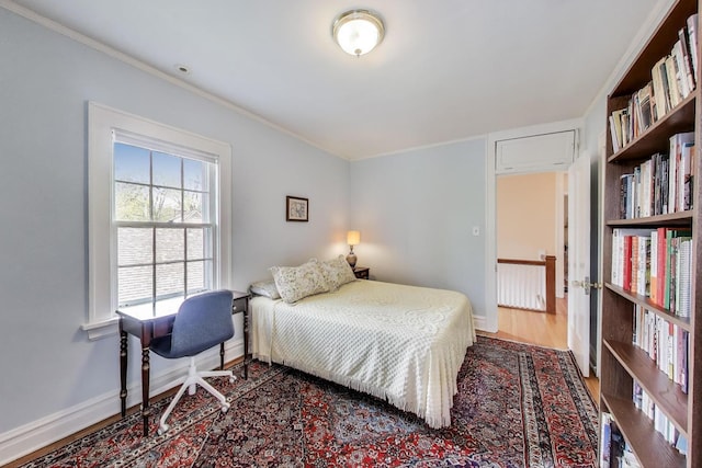 bedroom with ornamental molding, wood finished floors, and baseboards