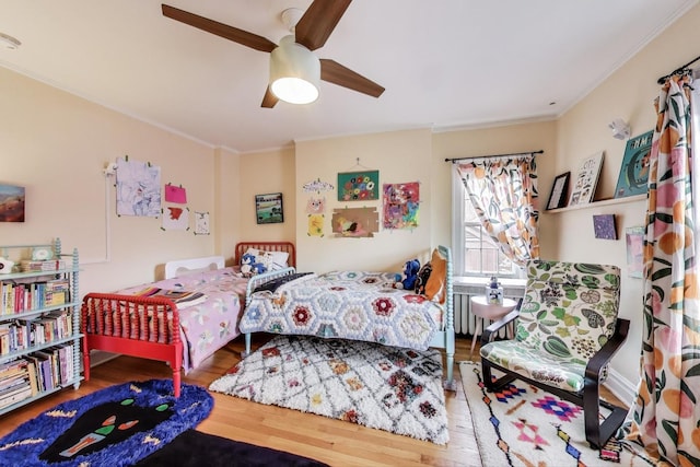 bedroom featuring radiator heating unit, crown molding, wood finished floors, and a ceiling fan