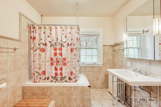 bathroom featuring tile walls, plenty of natural light, tiled shower / bath, a sink, and tile patterned flooring