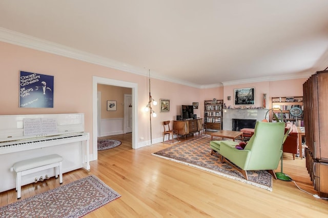 living area with ornamental molding, wood finished floors, and a fireplace