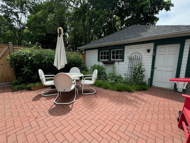 view of patio / terrace featuring fence, outdoor dining space, and an outbuilding