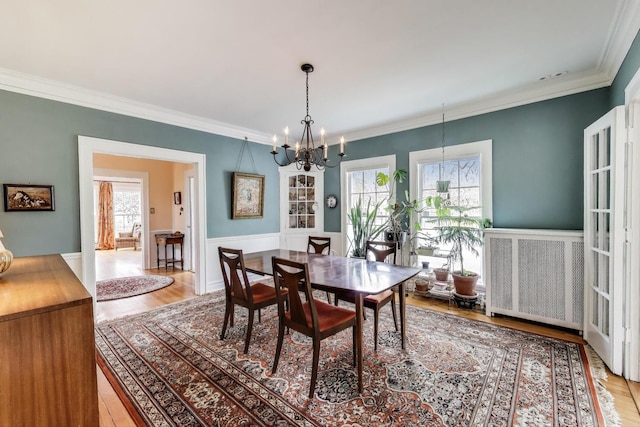 dining space with a chandelier, plenty of natural light, crown molding, light wood-style floors, and wainscoting