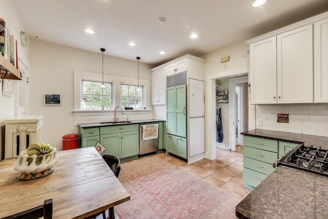 kitchen featuring green cabinetry, paneled built in fridge, stainless steel dishwasher, a sink, and backsplash