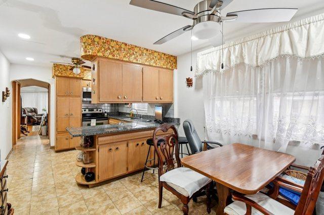 5058 S Ridgeway Ave, Chicago, IL 60632 - kitchen featuring light tile patterned flooring, open shelves, appliances with stainless steel finishes, a ceiling fan, and a peninsula