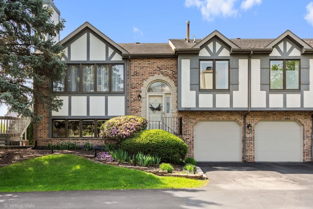 view of front of property with brick siding, an attached garage, stucco siding, and aphalt driveway