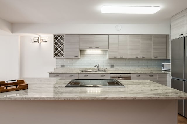 kitchen with a sink, appliances with stainless steel finishes, decorative backsplash, and modern cabinets