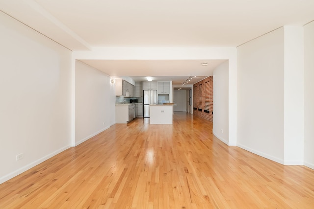 unfurnished living room with light wood-style flooring and baseboards