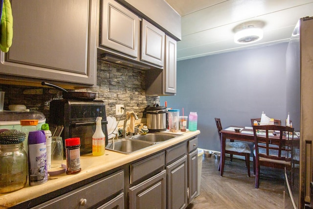 kitchen featuring a sink, decorative backsplash, gray cabinetry, and light countertops