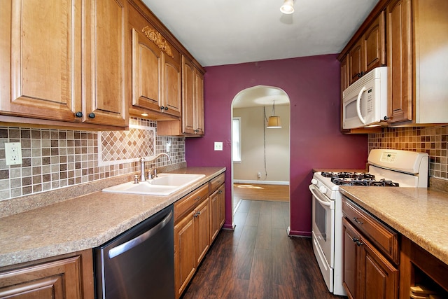 566 N 10th Ave, Kankakee, IL 60901 - kitchen with white appliances, a sink, arched walkways, baseboards, and dark wood-type flooring