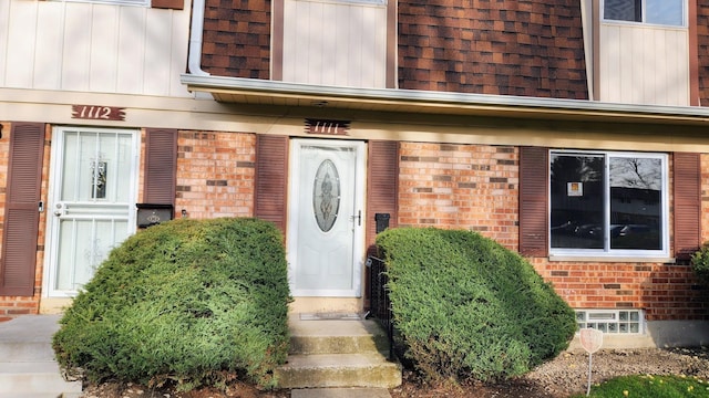 property entrance featuring board and batten siding and brick siding