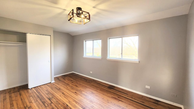 unfurnished bedroom featuring a closet, baseboards, and hardwood / wood-style floors