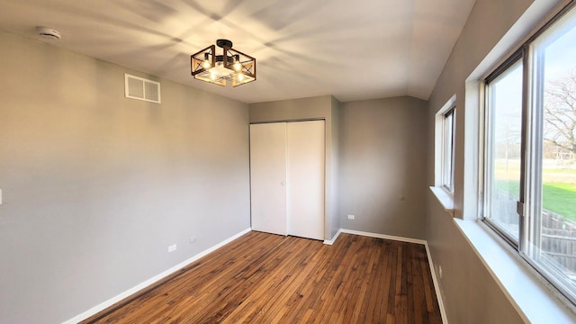 unfurnished bedroom with visible vents, wood-type flooring, baseboards, and multiple windows
