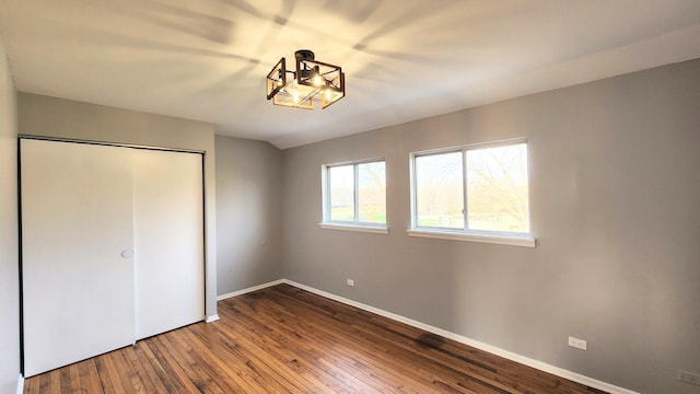unfurnished bedroom with wood-type flooring, baseboards, and a closet