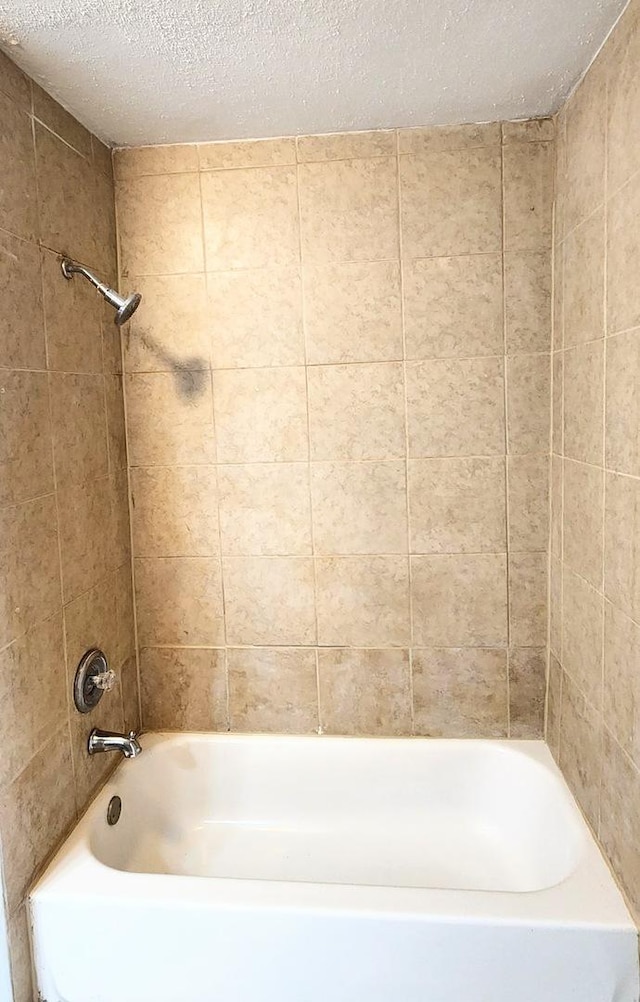 bathroom with a textured ceiling and shower / bathing tub combination