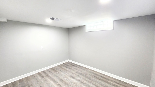 basement with baseboards, visible vents, and light wood finished floors