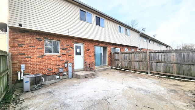 back of house with a patio, a fenced backyard, central AC, and brick siding
