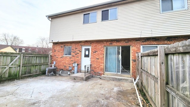 rear view of property featuring entry steps, a fenced backyard, a patio area, and brick siding