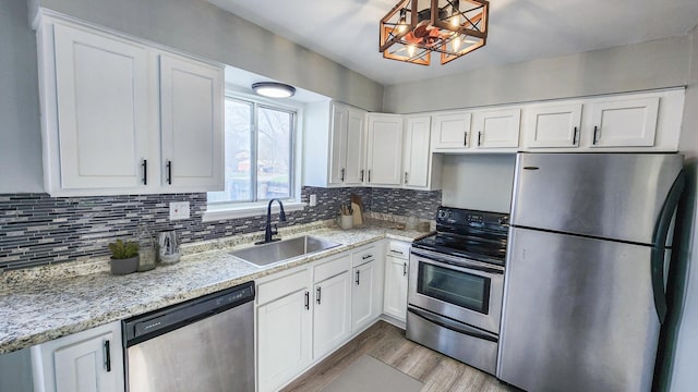 kitchen featuring white cabinets, stainless steel appliances, a sink, and light wood finished floors