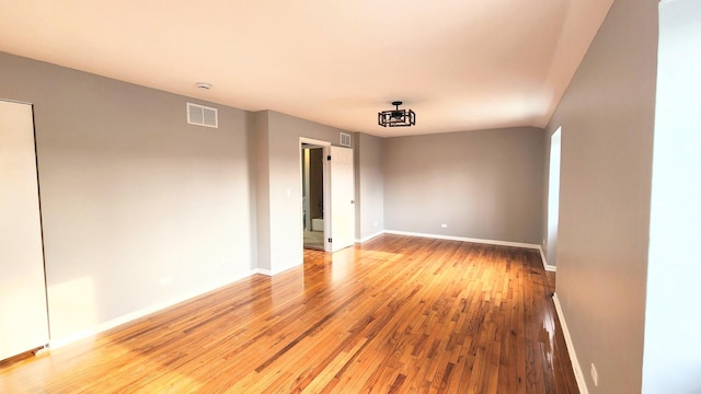 empty room featuring baseboards, light wood-type flooring, and visible vents