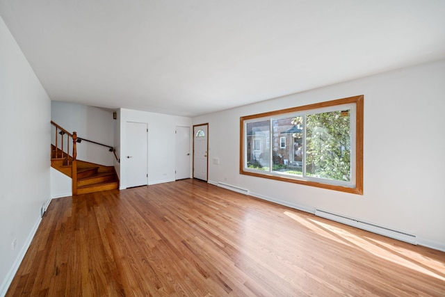 unfurnished living room with baseboard heating, stairway, baseboards, a baseboard radiator, and light wood finished floors