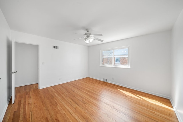 empty room featuring a ceiling fan, baseboards, visible vents, and light wood finished floors