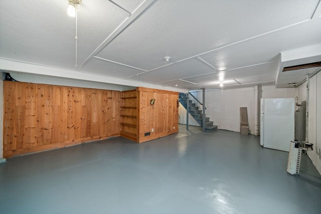 finished basement featuring freestanding refrigerator and stairs