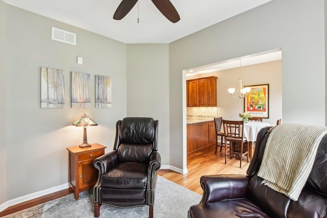 1565 Ashbury Pl, Lemont, IL 60439 - living area with baseboards, visible vents, light wood-style flooring, and ceiling fan with notable chandelier
