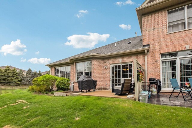 1565 Ashbury Pl, Lemont, IL 60439 - rear view of house featuring fence, a shingled roof, brick siding, a lawn, and a patio