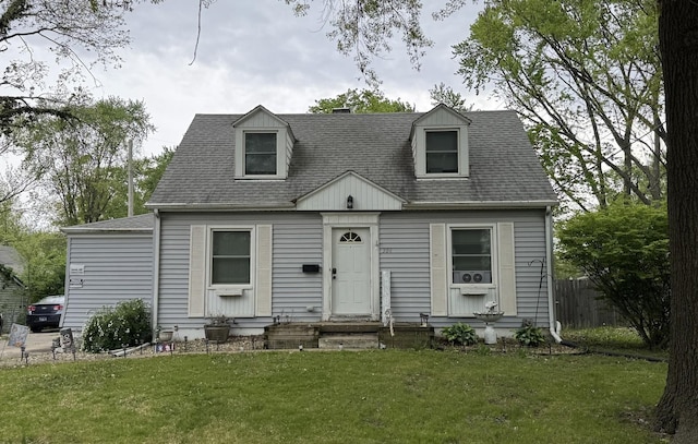 cape cod house with fence, roof with shingles, and a front lawn