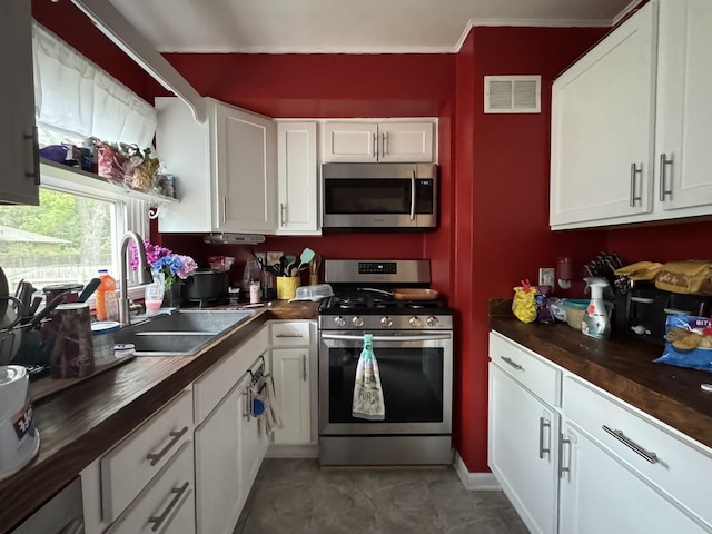 kitchen featuring appliances with stainless steel finishes, butcher block counters, a sink, and visible vents