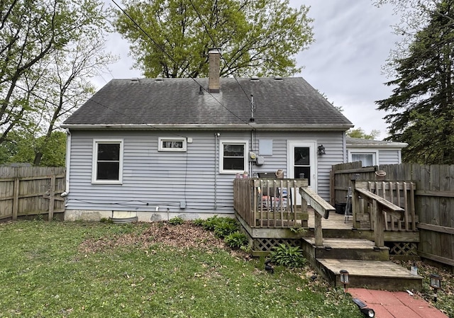 rear view of house with fence, a wooden deck, a chimney, and a lawn