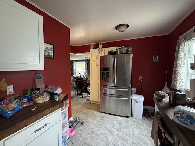 kitchen with crown molding, light floors, a healthy amount of sunlight, and stainless steel fridge with ice dispenser