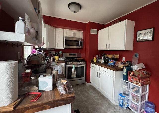 kitchen featuring visible vents, white cabinetry, crown molding, and stainless steel appliances