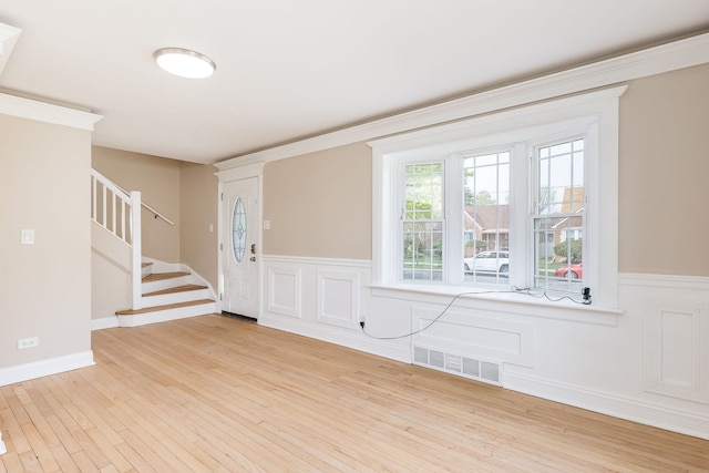 foyer featuring stairway, wainscoting, wood finished floors, and visible vents