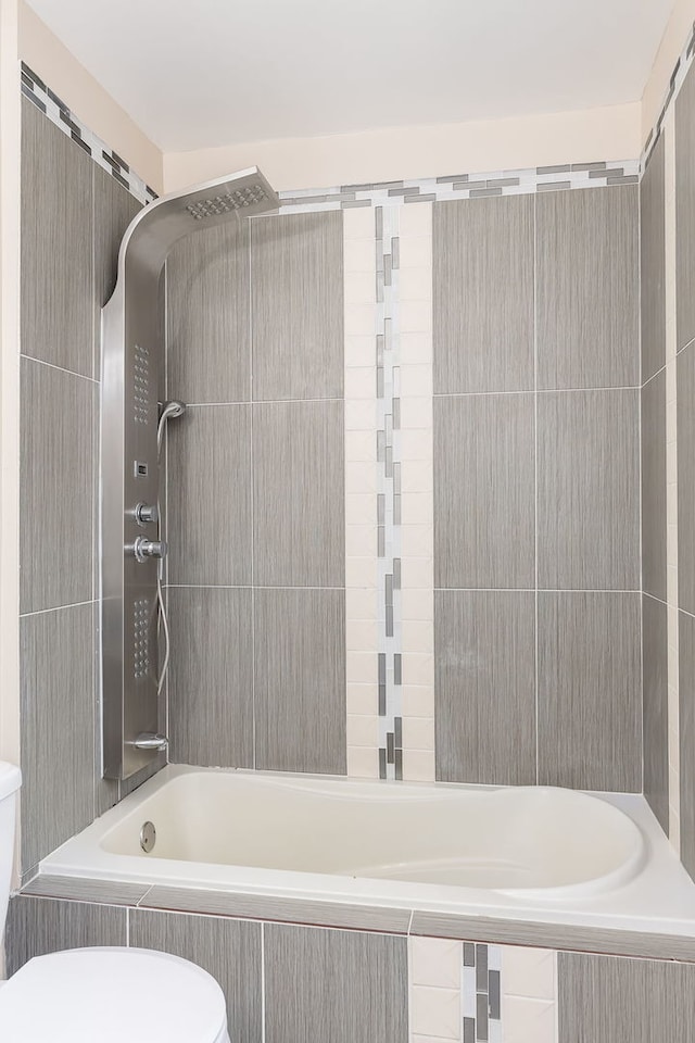 bathroom with toilet and tiled shower / bath