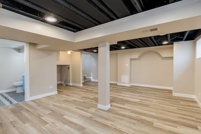 finished below grade area with stairway, baseboards, wood finished floors, and visible vents