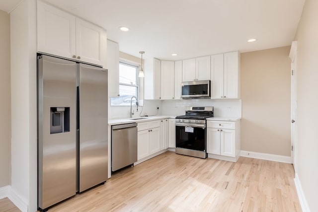 kitchen featuring white cabinets, appliances with stainless steel finishes, a sink, light wood finished floors, and light countertops