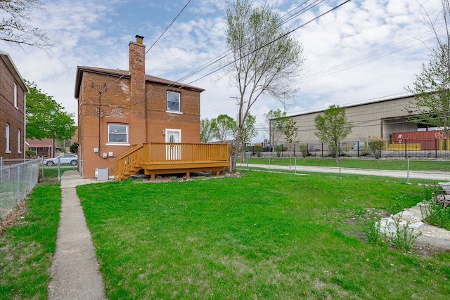 rear view of property with a yard, a deck, a chimney, and fence private yard