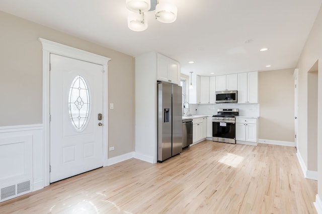 kitchen featuring a sink, light wood-style floors, stainless steel appliances, and white cabinetry