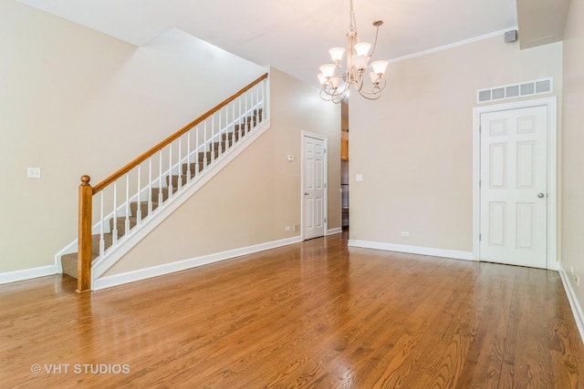 unfurnished dining area featuring stairway, a chandelier, wood finished floors, and baseboards