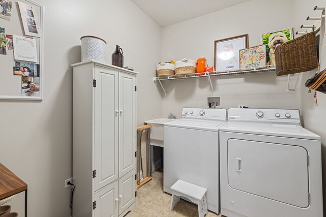 laundry room with independent washer and dryer, light tile patterned floors, and cabinet space