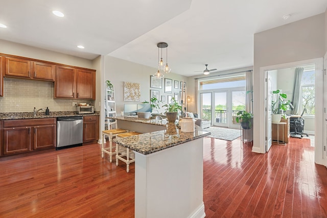 kitchen featuring stainless steel dishwasher, decorative backsplash, a healthy amount of sunlight, and dark wood-type flooring