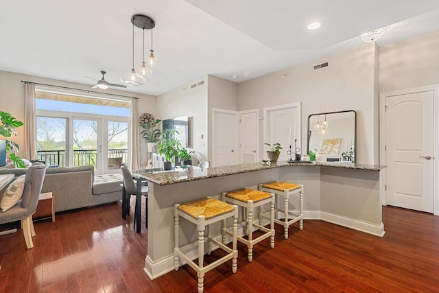 kitchen with visible vents, pendant lighting, light stone countertops, ceiling fan, and dark wood-style floors