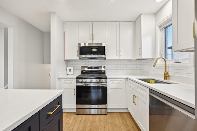 310 Muskegon Ave, Calumet City, IL 60409 - kitchen featuring white cabinets, a sink, light wood finished floors, light countertops, and stainless steel appliances