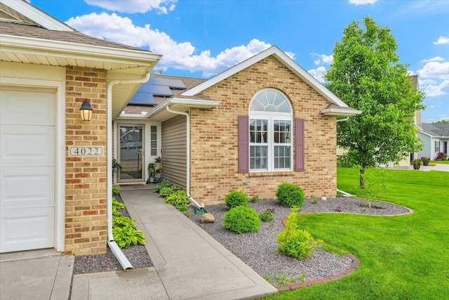 4022 Orchard Ln, Monticello, IL 61856 - property entrance with a lawn, roof mounted solar panels, brick siding, and an attached garage